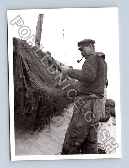 Stará fotografie rybář s dýmkou opravuje sítě na pláži (BM26875)