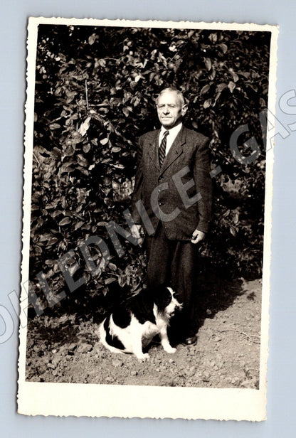 Stará fotografie muž v obleku s psem leží v zeleni (M26164)