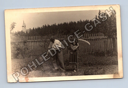 Stará fotografie Muž s kosou a dívka s hráběmi kostel v (M40446)